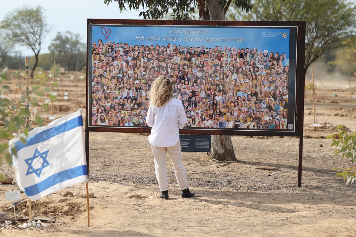 Женщина у стенда с фотографиями жертв на месте, где проходил музыкальный фестиваль Supernova 7 октября 2023 года, близ кибуца Реим, Израиль, 6 октября 2024 года. Фото: Abir Sultan / EPA