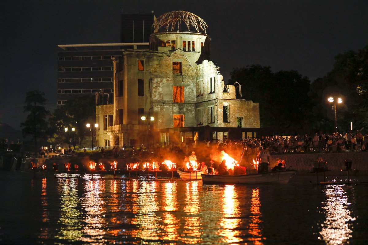 Участники церемонии зажигают огни на реке Мотоясу под куполом Гэмбаку, чтобы отдать дань памяти жертвам атомной бомбардировки 6 августа 1945 года в Мемориальном парке мира в Хиросиме, Япония, 5 августа 2017 года. Фото: Kimimasa Mayama / EPA