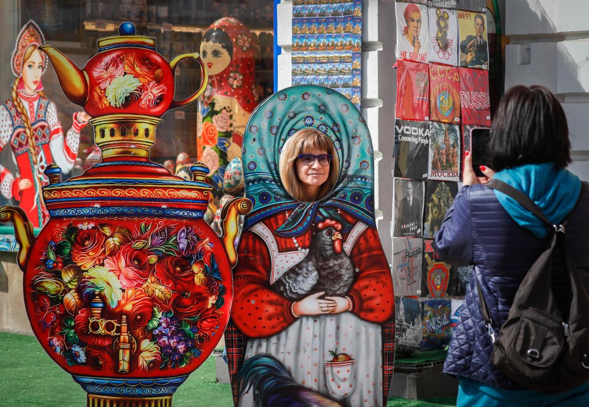 Туристы фотографируются с картонными матрешками перед сувенирным магазином в Москве, Россия, 14 апреля 2023 года. Фото: EPA-EFE/YURI KOCHETKOV