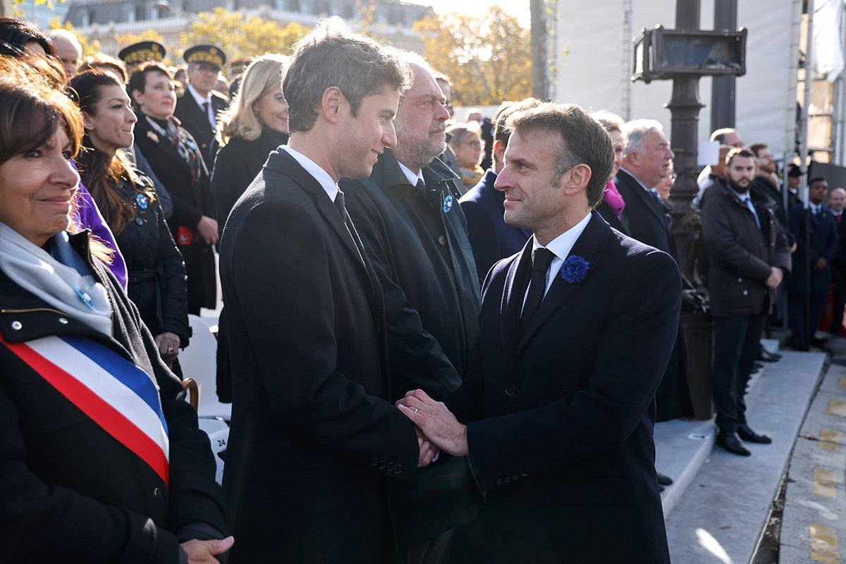 Президент Франции Эммануэль Макрон (справа) пожимает руку министру образования и молодежи Франции Габриэлю Атталю (слева) во время церемонии у Могилы Неизвестного солдата у Триумфальной арки в Париже, 11 ноября 2023. Фото: Ludovic Marin / EPA-EFE