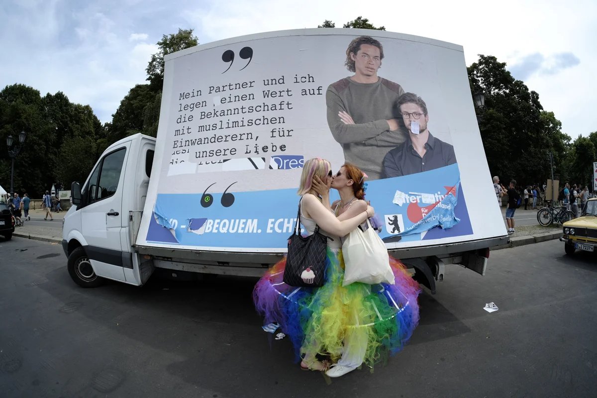 Two women kiss in front of a homophobic promotional poster for the far-right party Alternative for Germany (AfD), Berlin, 23 July 2016. Photo: snapshot-photography / K M Krause / Shutterstock / Rex Features / Vida Press