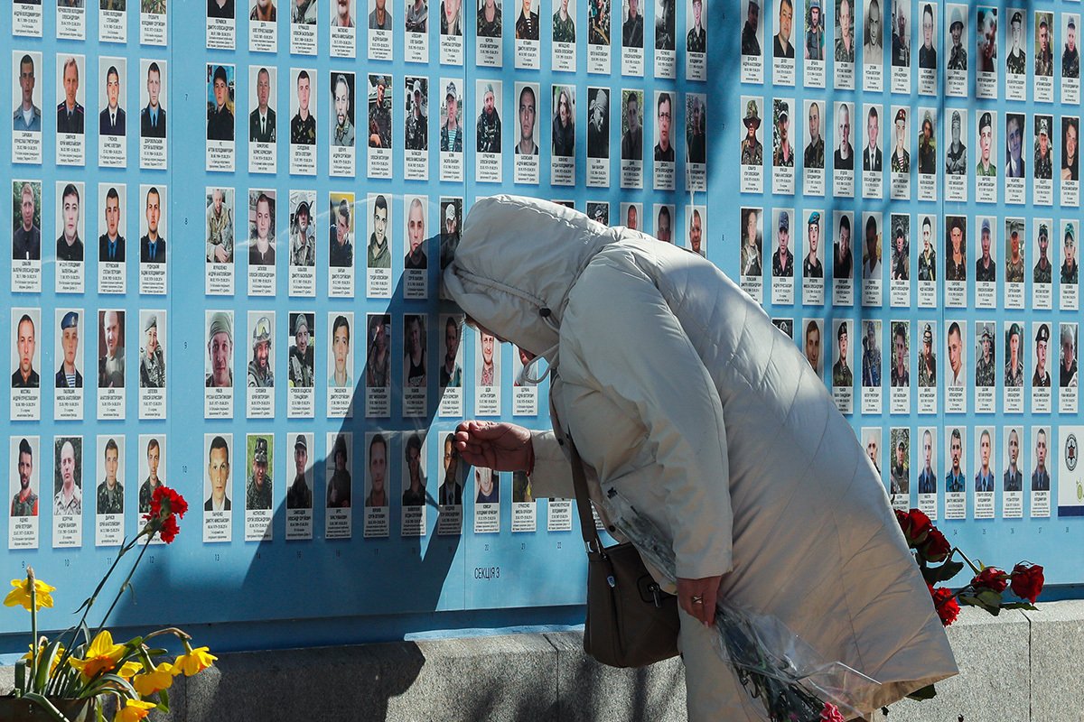 A woman touches the portrait of a loved one at the Memory Wall commemorating fallen Ukrainian soldiers in Kyiv, 14 March 2023. Photo: EPA-EFE/SERGEY DOLZHENKO