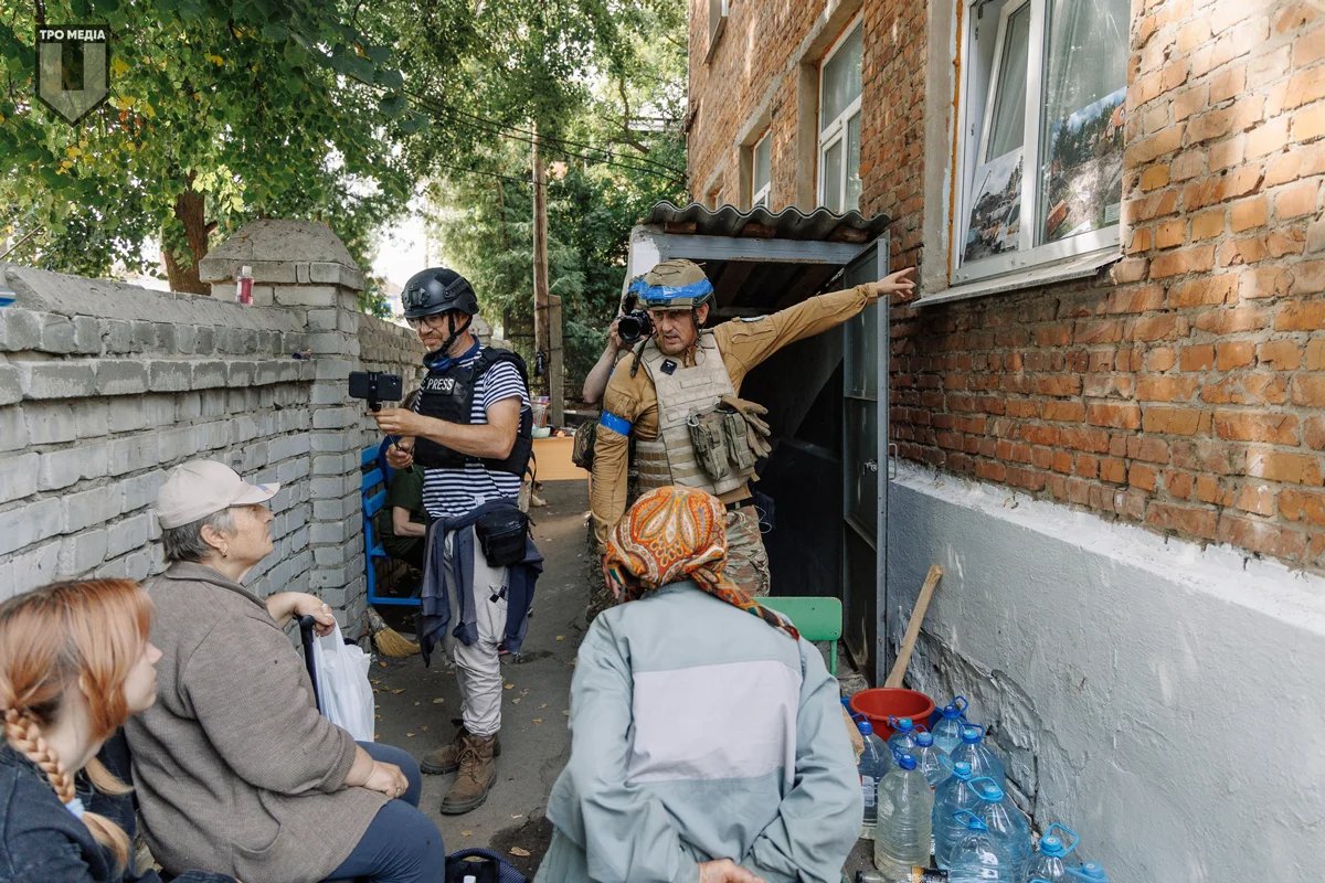 Oleksiy Dmytrashkovsky shows Sudzha residents photographs of the destruction left by Russian forces in Ukraine, August 2024. Photo: TRO Media / Facebook