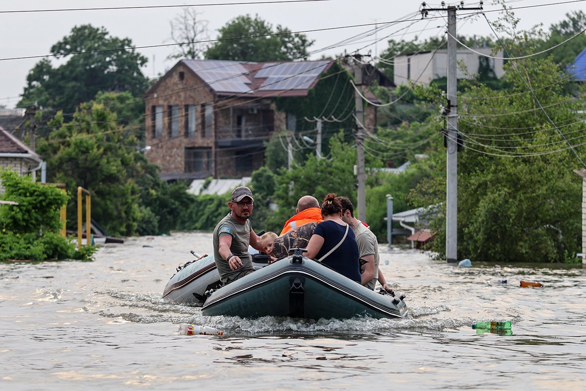 Люди в лодке на затопленной улице Херсона, Украина, 7 июня 2023 года. Фото: Микола Тимченко / EPA-EFE