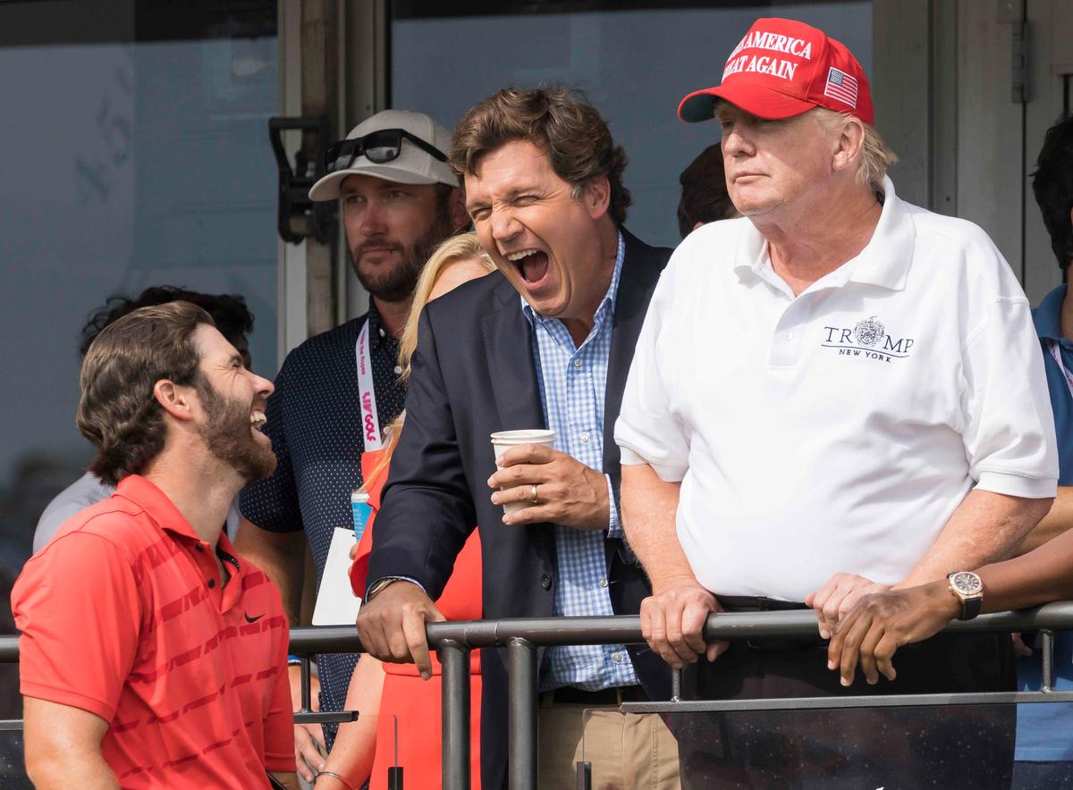 Такер Карлсон (в центре) и Дональд Трамп (справа) во время турнира по гольфу, июль 2022 года. Фото: EPA-EFE / JUSTIN LANE
