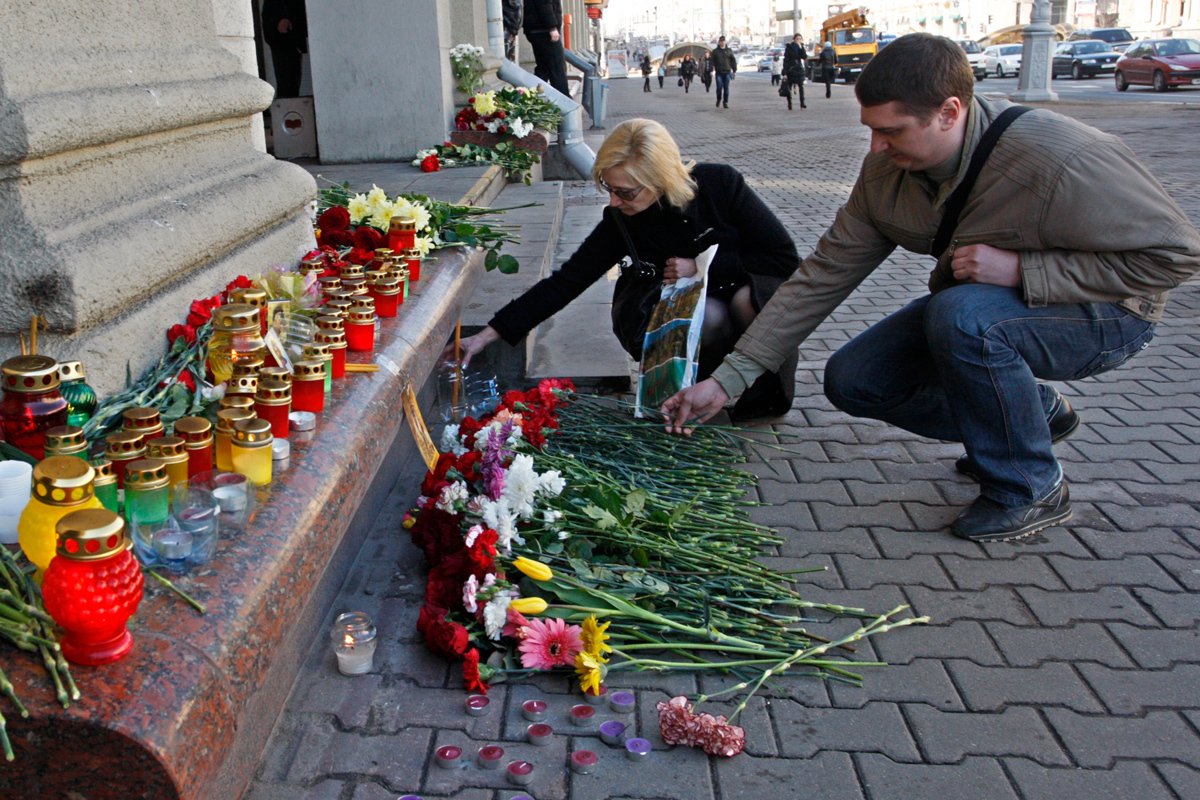 Люди возлагают цветы и зажигают свечи, чтобы отдать дань памяти жертвам взрыва на станции метро «Октябрьская» в центре Минска, 12 апреля 2011 года
