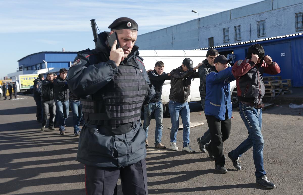 Russian police round up suspected illegal migrants during a raid on a Moscow warehouse, 14 October 2013. Photo: EPA / MAXIM SHIPENKOV