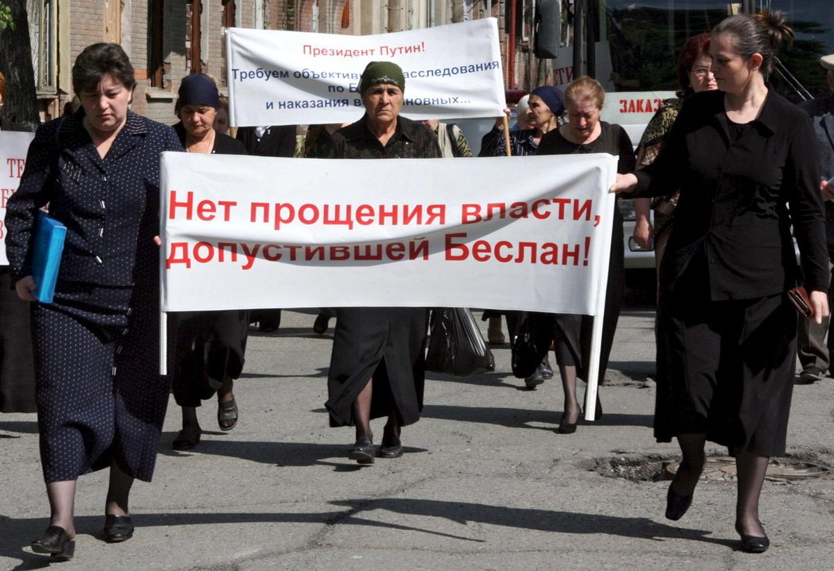 Родственники жертв трагедии в Беслане держат плакаты с требованием справедливого расследования теракта, направляются в Верховный суд Северной Осетии, 24 мая 2006 года, где продолжается оглашение приговора единственному оставшемуся в живых захватчику заложников в Беслане Нурпаши Кулаеву. Фото: Zurab Kurtsikidze/EPA