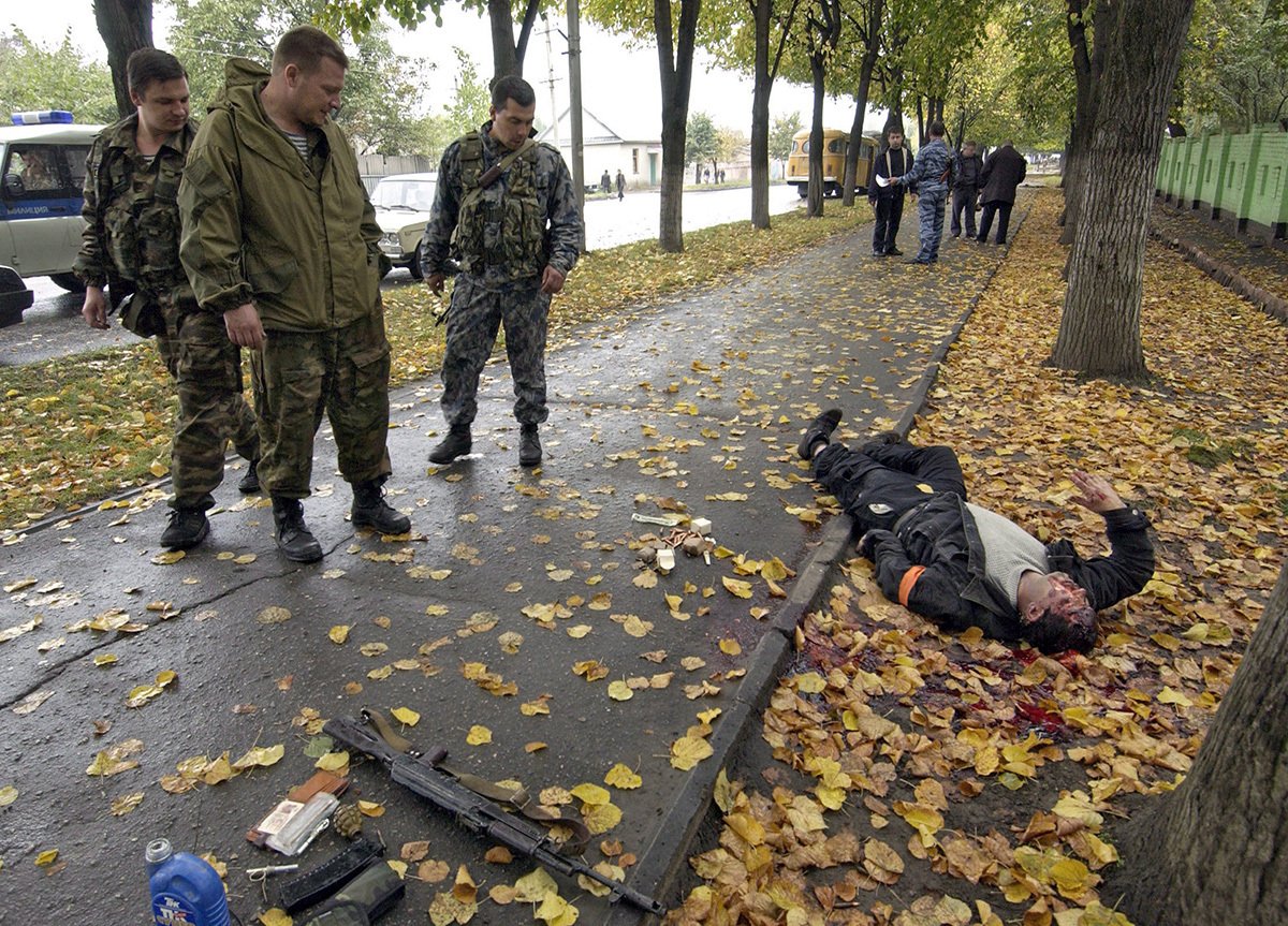 Милиционеры смотрят на убитого боевика в городе Нальчик, 14 октября 2005 года. Фото: Stringer / EPA
