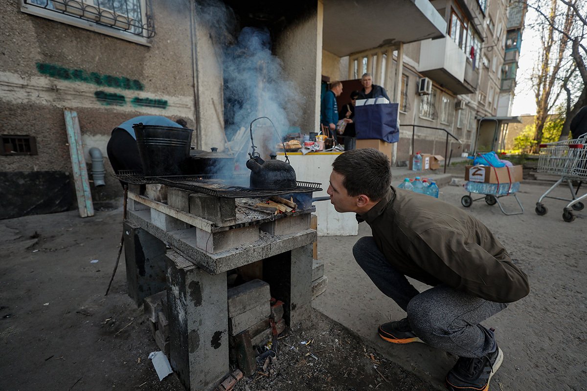 Горожане готовят еду возле своего жилого дома в Мариуполе, Украина, 29 апреля 2022 года. Фото: Сергей Ильницкий / EPA-EFE