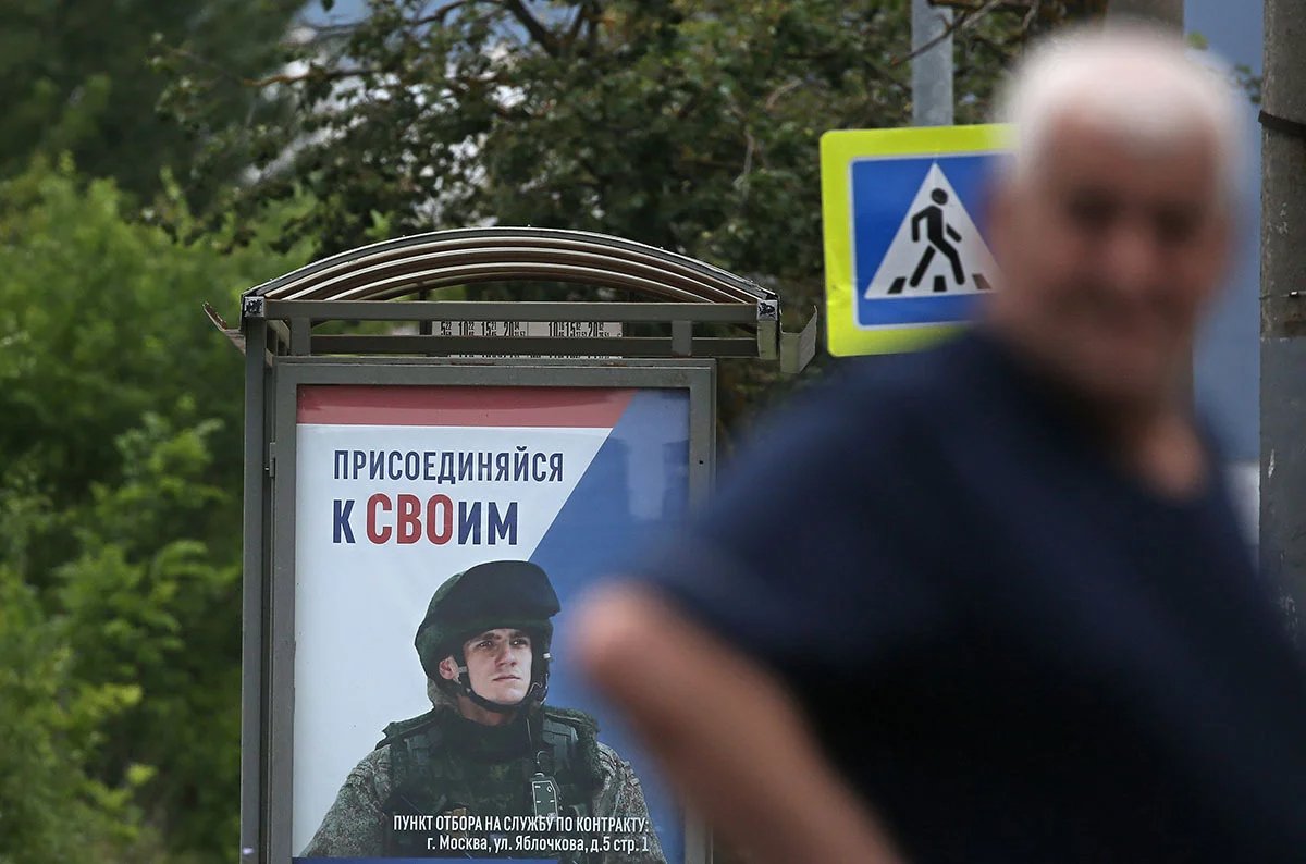 A man walks past a draft ad showing a Russian soldier with the caption “Join your people”. Photo: Maxim Shipenkov / EPA-EFE