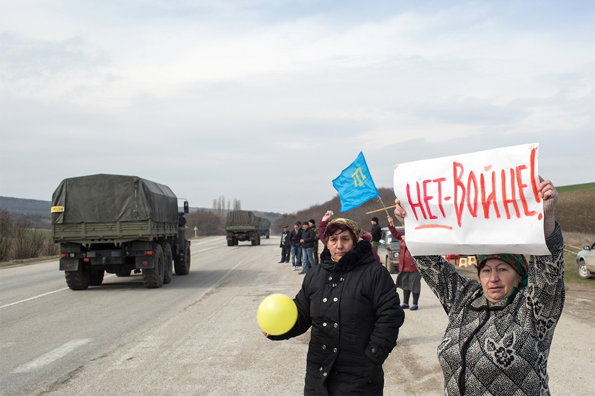 Крымские этнические татары с плакатом «Нет войне!» в поселке Кок-Асан, примерно в 70 км от Симферополя, Крым, Украина, 8 марта 2014 года. Фото: Денис Синяков / EPA
